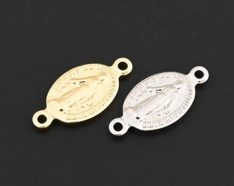 May include: Two oval-shaped religious pendants. One is gold-colored, the other is silver-colored. Each pendant has a small loop at each end. The pendants feature a detailed relief of a religious figure. The background is a solid black.