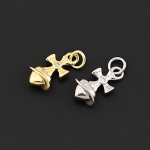 May include: Two small cross-shaped pendants. One is gold-colored, the other is silver-colored. Each pendant has a small, clear gemstone at the center of the cross and a loop at the top for attaching to a chain or other jewelry component.