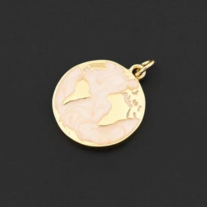 Peut inclure: Pendentif doré en forme de globe terrestre, rempli d'émail rose clair. Le pendentif présente des continents découpés et une petite boucle pour l'attacher à une chaîne. Le fond est noir uni.