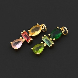 May include: Two gold-colored pendants, each featuring a series of colorful gemstones. One pendant has pink, red, and yellow stones, while the other has green and blue-green stones. The gemstones are in various shapes, including teardrop and rectangular cuts.