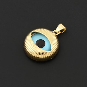 May include: Gold-colored pendant featuring a blue eye with a black pupil. The pendant has a circular shape with a ribbed texture around the eye and a small loop for a chain. The background is a solid black.