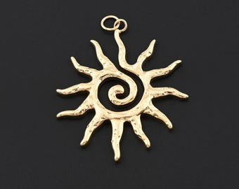 Puede incluir: Un colgante dorado en forma de sol con un centro en espiral y rayos puntiagudos. El colgante tiene un pequeño lazo en la parte superior para colgarlo. El fondo es negro sólido.