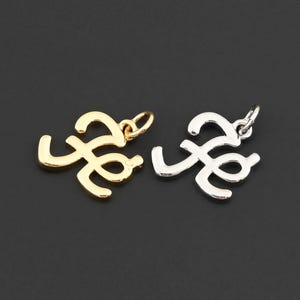 May include: Two metal pendants in a cursive letter design. One pendant is gold-colored, and the other is silver-colored. Both pendants have a small loop at the top for attaching to a chain or other jewelry component. The background is a solid black.