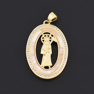 May include: Gold-tone oval pendant featuring a saint figure within a mother-of-pearl center. The pendant is outlined with small, clear crystals and has a bail for a chain. The design is set against a dark background.