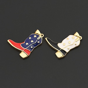 May include: Two gold-toned cowboy boot charms. One boot features a red toe, blue shaft with white stars, and gold accents. The other boot has a black toe, white shaft with gold stars, and gold accents. Both have a loop for attaching.