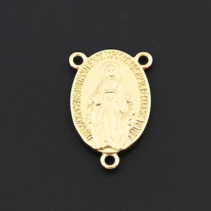 May include: Gold-colored oval pendant with a religious figure and text. The pendant has three small loops for attachment and is set against a dark background. The figure is in the center of the pendant.