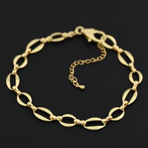 May include: A gold-colored bracelet with an oval link chain design. The bracelet has a lobster clasp closure and an adjustable chain. The jewelry is displayed on a black background.