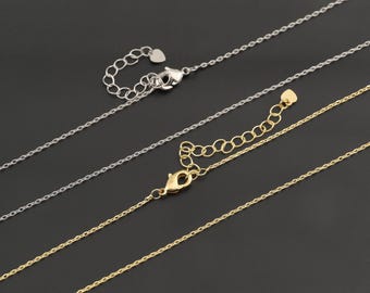 May include: Two delicate metal chains, one silver-toned and one gold-toned, each featuring a fine link design. Both chains include a lobster claw clasp, an adjustable extender section with circular links, and a small heart-shaped charm at the end.