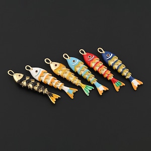 May include: Six colorful fish-shaped pendants with gold-tone accents. Each pendant features a unique color scheme, including black, white, orange, gold, blue, and red. The fish have detailed scales and fins, and a loop for attaching to a chain or other jewelry.