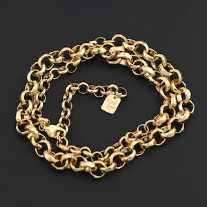 Może przedstawiać: Złoty naszyjnik z łańcuszkiem o grubym splocie. Naszyjnik posiada małą prostokątną zawieszkę z napisem "Good Luck". Łańcuszek jest prezentowany na czarnym tle.