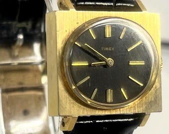 Timex Vintage Ladies Mechanical Wristwatch Square Gold Toned Case Black Sunburst Dial Stick Markers Black Leather Strap Sixty Seventy Era