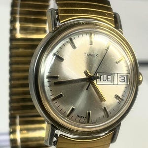 May include: A white ceramic mug with a black handle and the text "But First, Coffee" in a handwritten style. The mug is on a white surface. The mug is approximately 4 inches tall.