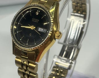 vintage Citizen 26mm quartz watch features a gold-plated stainless steel bracelet and a black dial with a date display