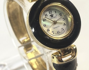 Cannes 26mm quartz analog watch with a gold-toned and black Rhinestone bracelet band. New Battery