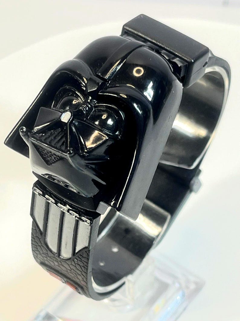 Pu&ograve; includere: Un orologio nero di Darth Vader con un design dettagliato del casco. L'orologio ha un cinturino nero con dettagli argentati e una chiusura rettangolare. Un oggetto da collezione.