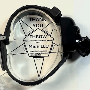 Pu&ograve; includere: Un porta orologio nero con una faccia trasparente, con il testo "THANK YOU" e "THROW Mich LLC". Il supporto ha un design di Darth Vader sul lato. Il porta orologio &egrave; progettato per contenere un orologio.