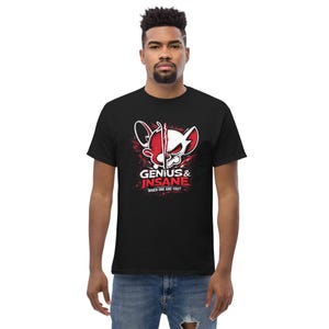Op de afbeelding: Zwart T-shirt met een cartoon muis grafiek, rood en wit gesplitst, en de tekst "GENIUS & INSANE" en "WHICH ONE ARE YOU?" in wit en rood. Het ontwerp heeft een spat effect.