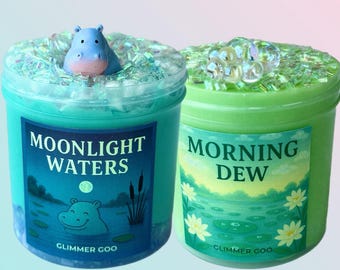 May include: Two jars of Glimmer Goo slime. One is teal with a hippo figurine and the words "Moonlight Waters." The other is green with the words "Morning Dew." Both jars have glitter and decorative elements.