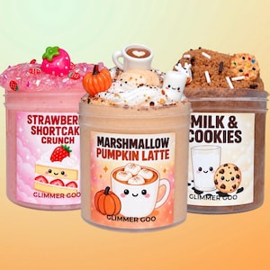Puede incluir: Tres frascos de plástico transparente con slime texturizado, etiquetados como Strawberry Shortcake Crunch, Marshmallow Pumpkin Latte y Milk & Cookies. Cada frasco tiene una etiqueta temática con ilustraciones y adornos decorativos.