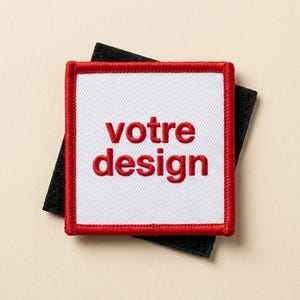 Puede incluir: Un parche cuadrado con centro blanco y borde rojo, con el texto bordado "votre design" en rojo. El parche está sobre un cuadrado negro, todo sobre un fondo beige.