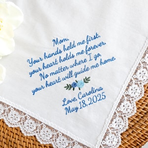May include: White handkerchief with blue embroidered text that reads "Mom. Your hands held me first, your heart holds me forever. No matter where I go, your heart will guide me home." Includes floral embroidery and lace trim. Signed "Love, Carolina May 18, 2025."