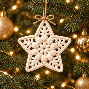 May include: A cream-colored, star-shaped crochet ornament featuring a textured, puff-stitch floral center and intricate openwork detailing. The ornament is suspended by a thin, natural-toned jute twine tied into a small bow at the top.