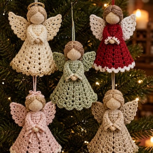 May include: Five crocheted angel ornaments hanging as decorations. Each angel features a round head, textured wings, and a flared dress in cream, sage green, deep red, soft pink, or tan. Some angels have gold halos or gold trim on the dress hem.