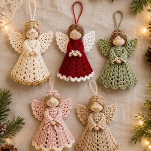 May include: Five handmade crochet angel ornaments with hanging loops. The angels feature tan yarn heads, textured wings, and dresses in cream, dark red, sage green, light pink, and beige. Some dresses have gold trim, and some angels wear gold halos.