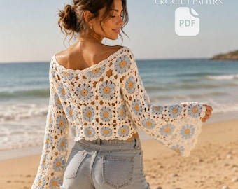 May include: A long-sleeved crochet crop top featuring a repeating pattern of white, light blue, and yellow daisy granny squares. The garment has a wide neckline and flared sleeves. Text in the image reads: BOHO DAISY GRANNY SQUARE CROP TOP CROCHET PATTERN PDF.