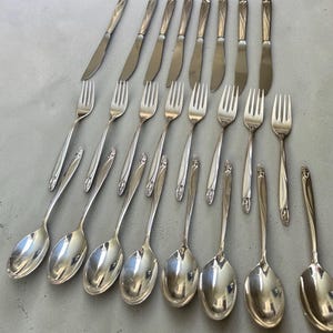 Puede incluir: Una taza de cerámica blanca con un asa negra y el texto "But First, Coffee" en un estilo manuscrito. La taza está sobre una superficie blanca. La taza mide aproximadamente 10 cm de alto.