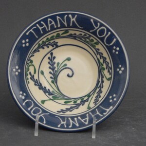 May include: A blue and white ceramic bowl with a green floral design and the words "Thank You" written around the rim.