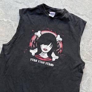 Könnte beinhalten: Schwarzes ärmelloses T-Shirt mit einer Grafik einer Frau mit schwarzen Haaren, roten Lippen und einem rot-weißen Design. Der Text "YEAH YEAH YEAH" ist darunter gedruckt. Das Shirt ist aus weichem Material.