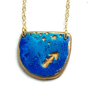 K&ouml;nnte beinhalten: Goldkette mit einem blauen und goldenen Anh&auml;nger mit dem Sternzeichen Sch&uuml;tze.