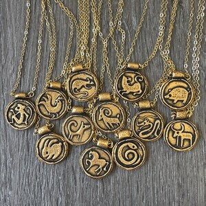 May include: Gold-colored pendant necklaces with zodiac symbols. Each pendant features a different animal design, including a rat, rooster, and rabbit, on a circular base. The necklaces have delicate gold chains.