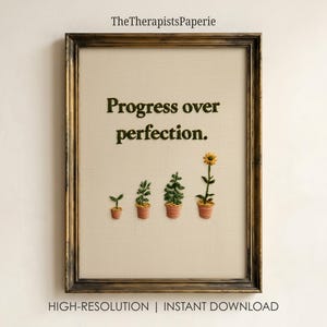 Może przedstawiać: Oprawiona haftowana grafika na kremowym materiale z ciemnozielonym napisem 'Progress over perfection.' Poniżej tekstu znajdują się cztery wyhaftowane rośliny doniczkowe w różnych fazach wzrostu, kończące się żółtym słonecznikiem w terakotowej doniczce.