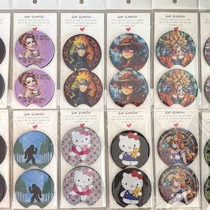 May include: A collection of car coasters with various designs. Some feature cartoon characters, anime figures, and humorous phrases. The coasters are round and made of a glossy material, with a black base and colorful graphics.