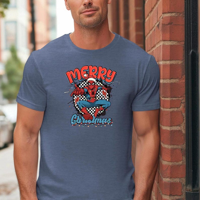 Puede incluir: Camiseta azul con un dise&ntilde;o de Spider-Man con gorro de Pap&aacute; Noel y la frase "Merry Christmas". El dise&ntilde;o incluye un fondo a cuadros y detalles festivos. La camiseta es de color azul liso.
