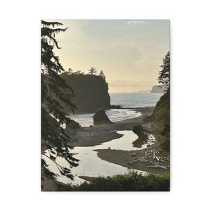 May include: A canvas print of a coastal landscape featuring a beach, ocean, and river. The scene is framed by trees and cliffs, with a warm, natural color palette. The sky is a soft, muted yellow, and the water reflects the light.