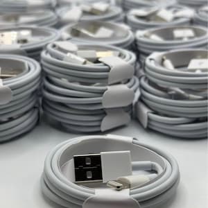以下が含まれることがあります： 整然と巻かれた白いUSB充電ケーブルのコレクション。各ケーブルは白いストラップで固定され、USBと小型コネクタが付いています。ケーブルは積み重ねられており、バルク製品を示唆しています。