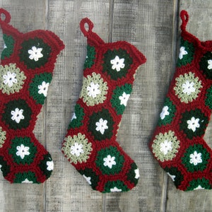 May include: Three crocheted Christmas stockings in red, green, and white with a snowflake pattern.