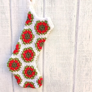 May include: A white crocheted Christmas stocking with red and green floral designs.