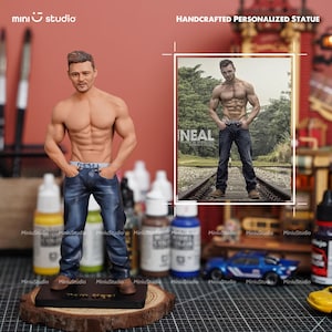 May include: A handcrafted personalized statue of a muscular man in blue jeans, with "DIESEL" on the waistband. The statue is on a wooden base. The image also includes a framed photo of the same man. The text "NEAL" is visible.