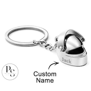Op de afbeelding: Een zilverkleurige sleutelhanger met een miniatuur motorhelm. De helm heeft een open vizier en de naam "Jack" is aan de zijkant gegraveerd. De sleutelhanger bevat ook een ring en een ketting. Tekst op de afbeelding zegt "Custom Name".