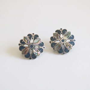 May include: A pair of silver earrings with a blue and iridescent abalone shell flower design.