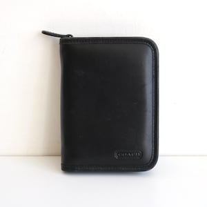 Cartera de mano pequeña con cremallera y diseño de agenda de Coach, de cuero negro