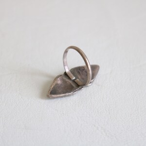 May include: A silver ring with a turquoise stone set in a silver setting. The ring is in the shape of a teardrop and has a silver band.