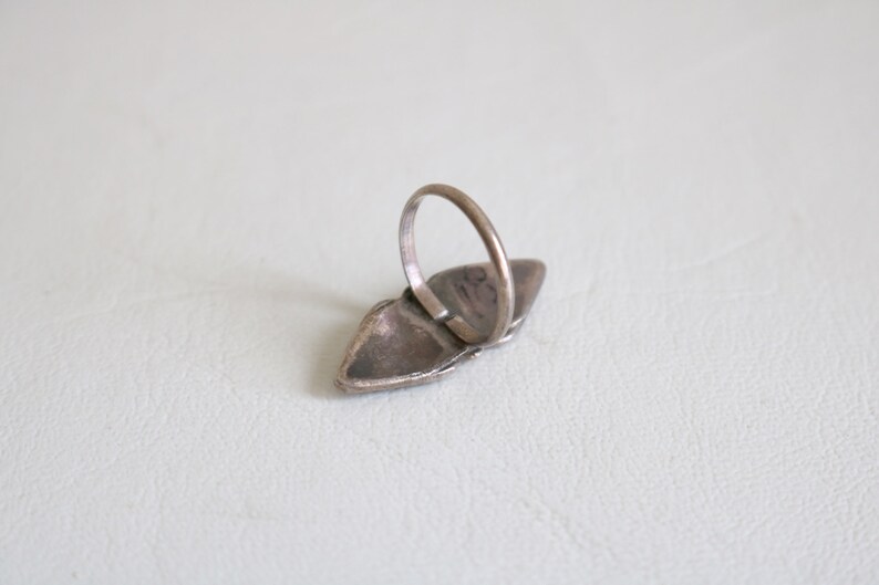 May include: A silver ring with a turquoise stone set in a silver setting. The ring is in the shape of a teardrop and has a silver band.