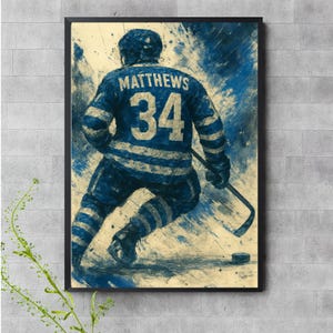 Puede incluir: Una camiseta de hockey azul y blanca con el nombre "MATTHEWS" y el número "34" en la espalda. La camiseta la lleva un jugador de hockey en una pose dinámica, con un fondo borroso de salpicaduras de pintura azul y blanca.