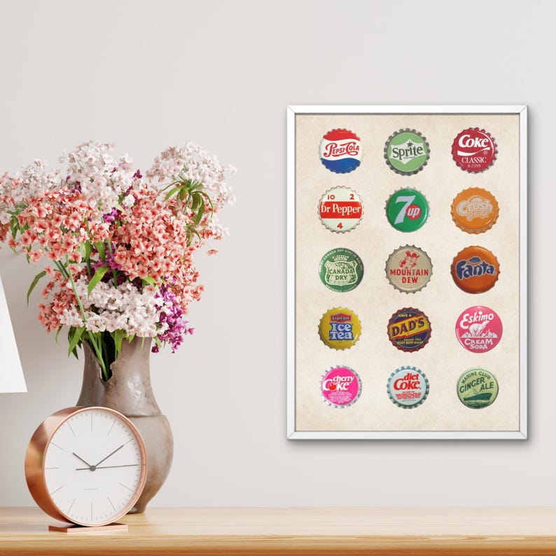 May include: A vintage-style print featuring 16 colorful soda bottle caps with various brand names, including Sprite, Coke, Dr Pepper, 7 Up, Mountain Dew, Fanta, and more. The print is on a cream-colored background and is framed in white.