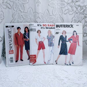 May include: Three sewing patterns for women's clothing. The patterns are from the brands Butterick and See & Sew. The patterns include a red jumpsuit, a red and white striped dress, and a red and white patterned shirt with white pants.